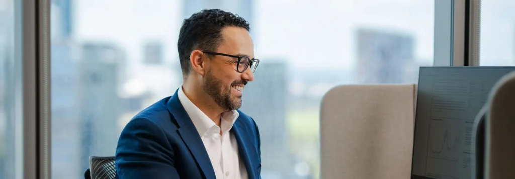 smiling genuinely while looking at financial data on a computer screen.